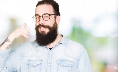 Uzun saç ve sakal yapıyor gülümseyen gözlüklü genç hipster adamla telefon hareketi ile el ve parmak telefonda konuşuyor gibi. Kavramları iletişim.