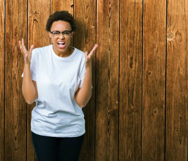 Güzel genç Afro-Amerikan kadın üzerinde gözlük takan arka plan deli izole ve deli bağırarak ve agresif ifade ve silah kaldırdı bağırıyor. Hayal kırıklığı kavramı.