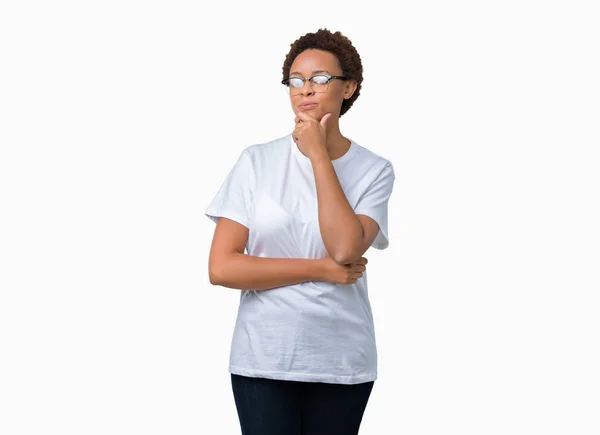 美丽的年轻非洲裔美国妇女戴眼镜在孤立的背景看起来自信的镜头与交叉的手臂和手提出的下巴上的微笑 积极的思考 — 图库照片