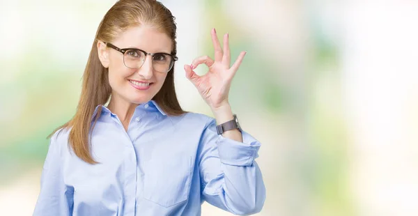 美しい中年成熟したビジネス女性が孤立した背景を浮かべて手と指で サインをしている肯定的な上メガネを着用します 成功した式 — ストック写真