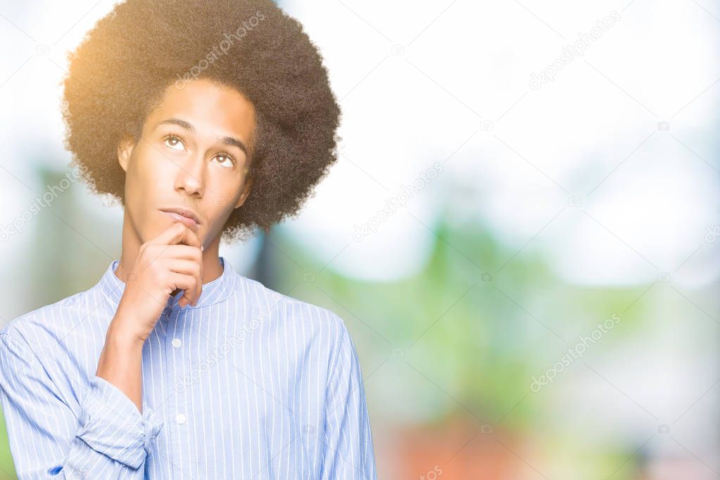 Young african american man with afro hair with hand on chin thinking about question, pensive expression. Smiling with thoughtful face. Doubt concept.