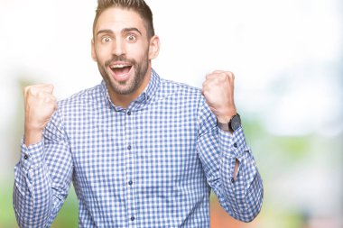 İzole arka plan kutlama üzerinde genç yakışıklı adam şaşırttı ve başarı için kaldırdı kollarını açarak hayret ve gözleri açık. Kazanan kavramı.