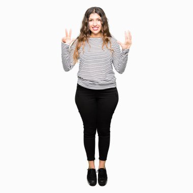 Şerit kazak gösteren ve parmak numarası sekiz ile işaret giyen genç güzel kadın emin ve mutlu gülümseyen iken.