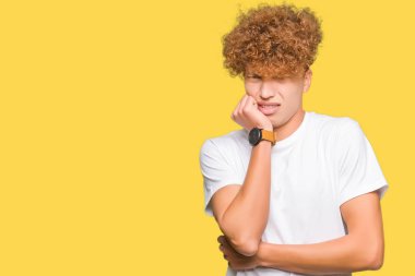 Afro saç ile genç yakışıklı adam rahat beyaz t-shirt görünümlü vurgulandı ve ağız ısırma çivi elleri ile gergin. Anksiyete sorunu.