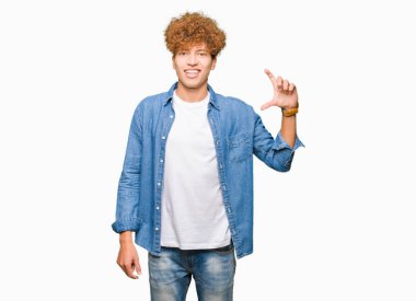 Genç yakışıklı adam afro saç giyen denim ceket gülümseyen ve emin işaret ile el yapıyor boyutu işareti yaparken parmaklar ve kamera bakıyor. Ölçü kavramı.