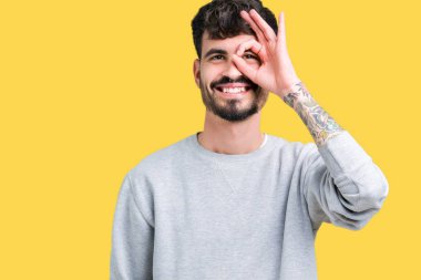 Gülümseyen, parmakları ile mutlu yüz üzerinden seyir göz el ile ok jest yapıyor izole arka plan üzerinde sweatshirt giyen genç yakışıklı adam.