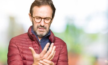 Orta yaş yakışıklı adam gözlük ve kış ceket giyiyor ellerde ve parmaklarda ağrı acı, artrit iltihabı