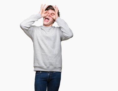 Dilini, parmaklarının arasından baktığını yapışmasını dürbün gibi ok jest yapıyor izole arka plan üzerinde sweatshirt giyen genç yakışıklı sportif adam. Deli ifade.