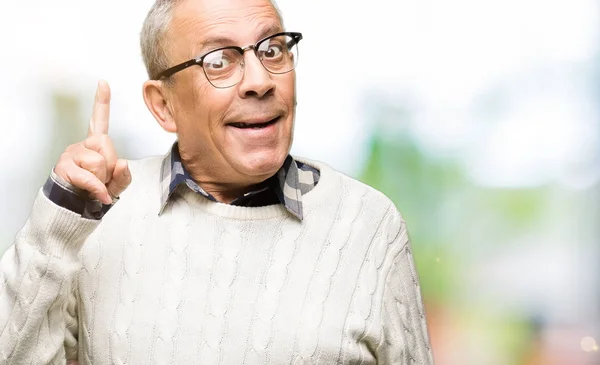 英俊的老人戴着眼镜和冬天的毛衣用手指指着成功的想法 离开和快乐 — 图库照片