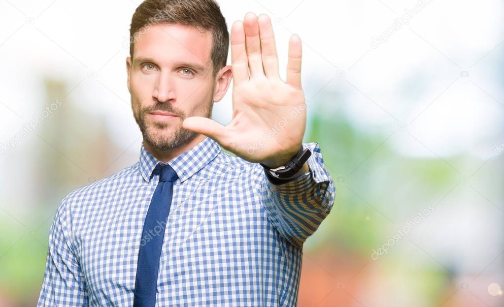 Handsome business man wearing tie doing stop sing with palm of the hand. Warning expression with negative and serious gesture on the face.