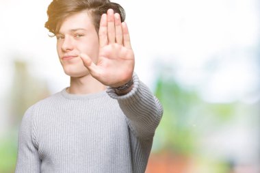 Yakışıklı delikanlı üzerinde kış kazak giyen elin avuç durağı şarkı yapıyor arka plan izole. Negatif ve ciddi bir jest yüz ifadesiyle uyarı.