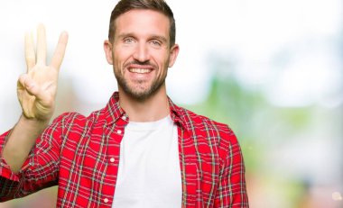 Yakışıklı adam kadar rahat gömlek gösterme ve işaret parmakları ile giyen üç kendinden emin ve mutlu gülümseyerek iken numara.