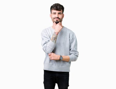 Emin çapraz kollar ve çeneme kaldırdı el ile gülümseme ile kameraya bakarak izole arka plan üzerinde kazak giyen genç yakışıklı adam. Pozitif düşünce.