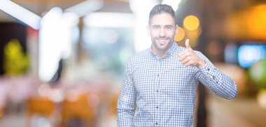 Yakışıklı delikanlı hareketi el ile mutlu yaşasın yapıyor izole arka plan üzerinde. Başarı gösteren kameraya bakarak ifade onaylama.