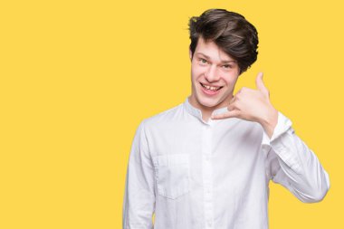 Genç yakışıklı iş adamı yapıyor gülümseyen izole arka plan üzerinde telefon hareketi ile el ve parmak telefonda konuşuyor gibi. Kavramları iletişim.