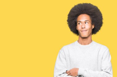 Afro saçlı görünümlü yan ve dik dik bakma uzağa düşünce gülümseyen sportif sweatshirt giyen genç Afro-Amerikan adam.