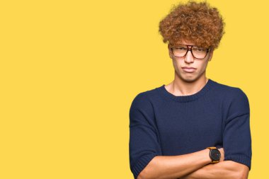 Afro yüz çapraz kolları üzerinde gözlük şüpheci ve sinir, onaylamayan ifade giyen genç yakışıklı adam. Negatif kişi.