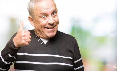 Hareketi el ile mutlu yaşasın yapıyor kış çizgili süveter giymiş yakışıklı komuta sizde. Kameraya bakarak başarı gösteren ile ifade onaylama.