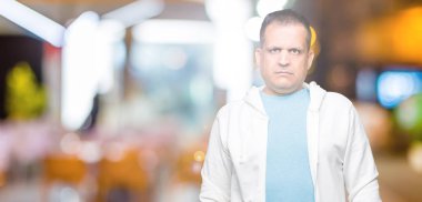 Üzerinde sweatshirt giyen orta yaş Arap adam arka plan gevşek yüzünde ciddi bir ifade ile izole. Basit ve doğal kameraya bakıyor.