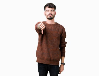 Mutsuz ve kızgın ret gösterilen ve başparmak aşağı hareketi ile negatif seyir izole arka plan üzerinde kış kazak giyen genç yakışıklı adam. Kötü ifade.