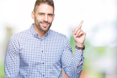 Kameraya bakarak yan el ve parmak ile işaret eden genç yakışıklı adam yüzünde kocaman bir gülümseme ile izole arka plan üzerinde.