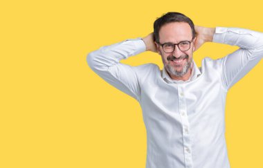 Yakışıklı Orta Çağ zarif kıdemli iş adamı izole arka plan üzerinde gözlük giyiyor rahatlatıcı ve baş ve boyun arkasındaki silah ve eller ile germe, mutlu gülümseyen