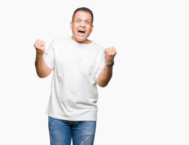 Kutlama izole arka plan üzerinde beyaz t-shirt şaşırttı ve silah ile başarı için hayran orta yaş Arap adam wearig kaldırdı ve gözleri açık. Kazanan kavramı.