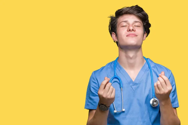 年轻的医生穿着医疗制服在孤立的背景做金钱手势用手 要求薪水付款 百万富翁企业 — 图库照片