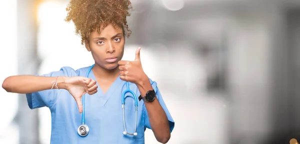 Young african american doctor woman over isolated background Doing thumbs up and down, disagreement and agreement expression. Crazy conflict