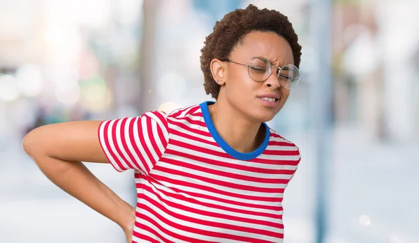 Beautiful young african american woman wearing glasses over isolated background Suffering of backache, touching back with hand, muscular pain