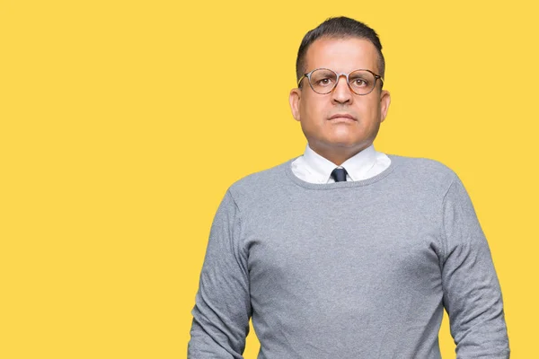 Middle age bussines arab man wearing glasses over isolated background Relaxed with serious expression on face. Simple and natural looking at the camera.