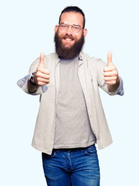 Onaylama gözlüklü genç sarışın adam el ile pozitif jest yapıyor gülümseyen ve başarı için mutlu yaşasın. Kamera, kazanan jest arıyorsunuz.