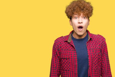 Afro saç ile genç yakışıklı öğrenci adam korkuyor ve sürpriz ifade, korku ve heyecanlı yüz ile şok bir ceket giyiyor.