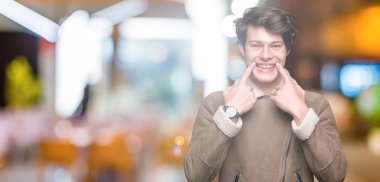 Genç yakışıklı adam giyen kış ceket izole üzerinde arka plan gülen açık ağız ile parmak işaret ve neşeli gülümseme zorlamadan