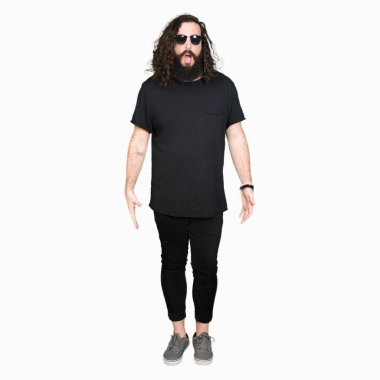 Genç hipster adam uzun saç ve sakal korkuyor ve şok sürpriz ifade, korku ve heyecan yüz ile güneş gözlüğü takıyor.
