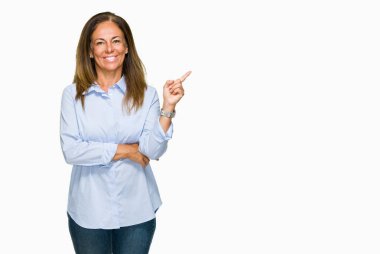 Kameraya bakarak yan el ve parmak ile işaret eden güzel orta yaş iş yetişkin kadın yüzünde kocaman bir gülümseme ile izole arka plan.