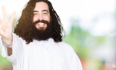 İsa Mesih kostüm gösterme ve işaret parmakları ile yukarı giyen adam kendinden emin ve mutlu gülümseyerek süre üçüncüsü.