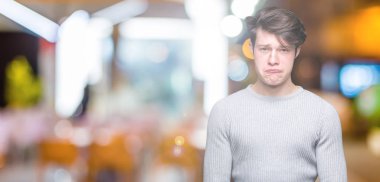 Yakışıklı delikanlı izole arka plan üzerinde kış kazak giyen depresif ve kızgın ve korkmuş ağlıyor sıkıntı için endişeleniyorum. Üzgün ifade.