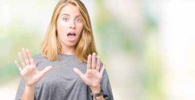 Şokta bağırarak korkuyor ve dehşet korku ifade dur hareketi el ile ile izole arka plan üzerinde büyük boy rahat t-shirt giyen güzel ve genç birbayan. Panik kavramı.