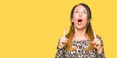 Leopar hayvan baskı elbise giyen güzel orta yaş kadın hayran ve bakmak ve parmaklar ve yükseltilmiş kollar ile işaret şaşırttı.