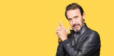 Orta yaş yakışıklı adam el hareketi ile sembolik silah tutan, çekim silah, kızgın yüz öldürmek oynamaya siyah deri ceket