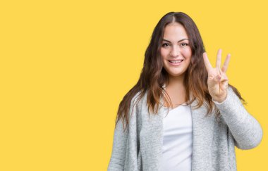 Parmakları ile kendinden emin ve mutlu gülümseyerek süre güzel artı boyutu genç kadın giyiyor kış ceket ve yukarıyı gösteren izole arka plan üzerinde üçüncüsü.