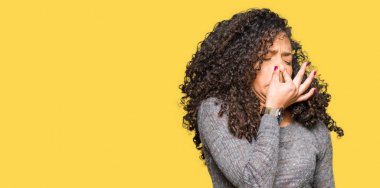 Kıvırcık saçlı Genç güzel kadın gri kazak kokmuş ve mide bulandırıcı bir şey kokuyor, dayanılmaz koku, burun parmaklar ile nefes tutarak. Kötü koku kavramı.