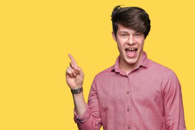 Kameraya bakarak yan el ve parmak ile işaret eden genç yakışıklı iş adamı yüzünde kocaman bir gülümseme ile izole arka plan üzerinde.