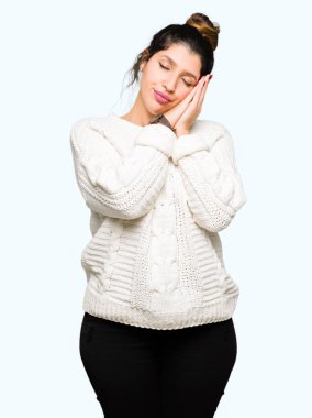 Rüya ve elleri ile kapalı gözler gülümseyen birlikte poz kış kazak uyku giyen genç güzel kadın yorgun.