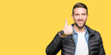 El ile jest kadar mutlu thumbs yapıyor kış ceket giyen yakışıklı adam. Başarı gösteren kameraya bakarak ifadeyi onaylama.