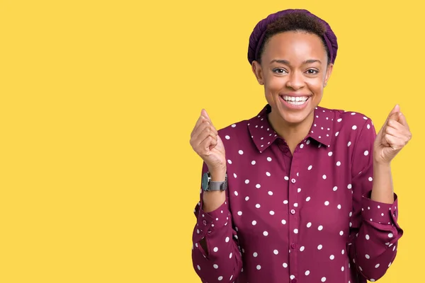 Beautiful young african american woman wearing head scarf over isolated background celebrating surprised and amazed for success with arms raised and open eyes. Winner concept.