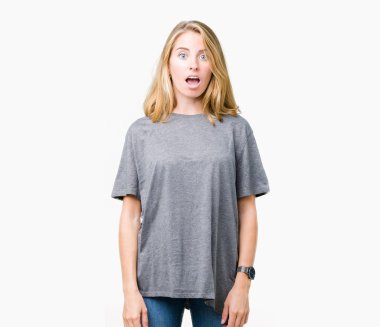 Korkuyor ve şok sürpriz ifade, korku ve heyecan yüz ile izole arka plan üzerinde büyük boy rahat t-shirt giyen güzel genç kadın.