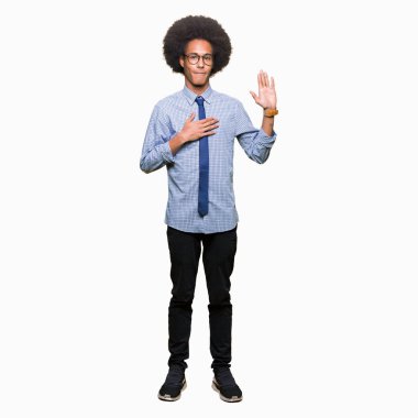 Young african american business man with afro hair wearing glasses Swearing with hand on chest and open palm, making a loyalty promise oath clipart