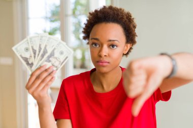 Kızgın yüz ile yirmi dolar banka banknotları tutan genç Afrikalı Amerikalı kadın, başparmak aşağı, ret kavramı ile sevmediğimi gösteren negatif işareti